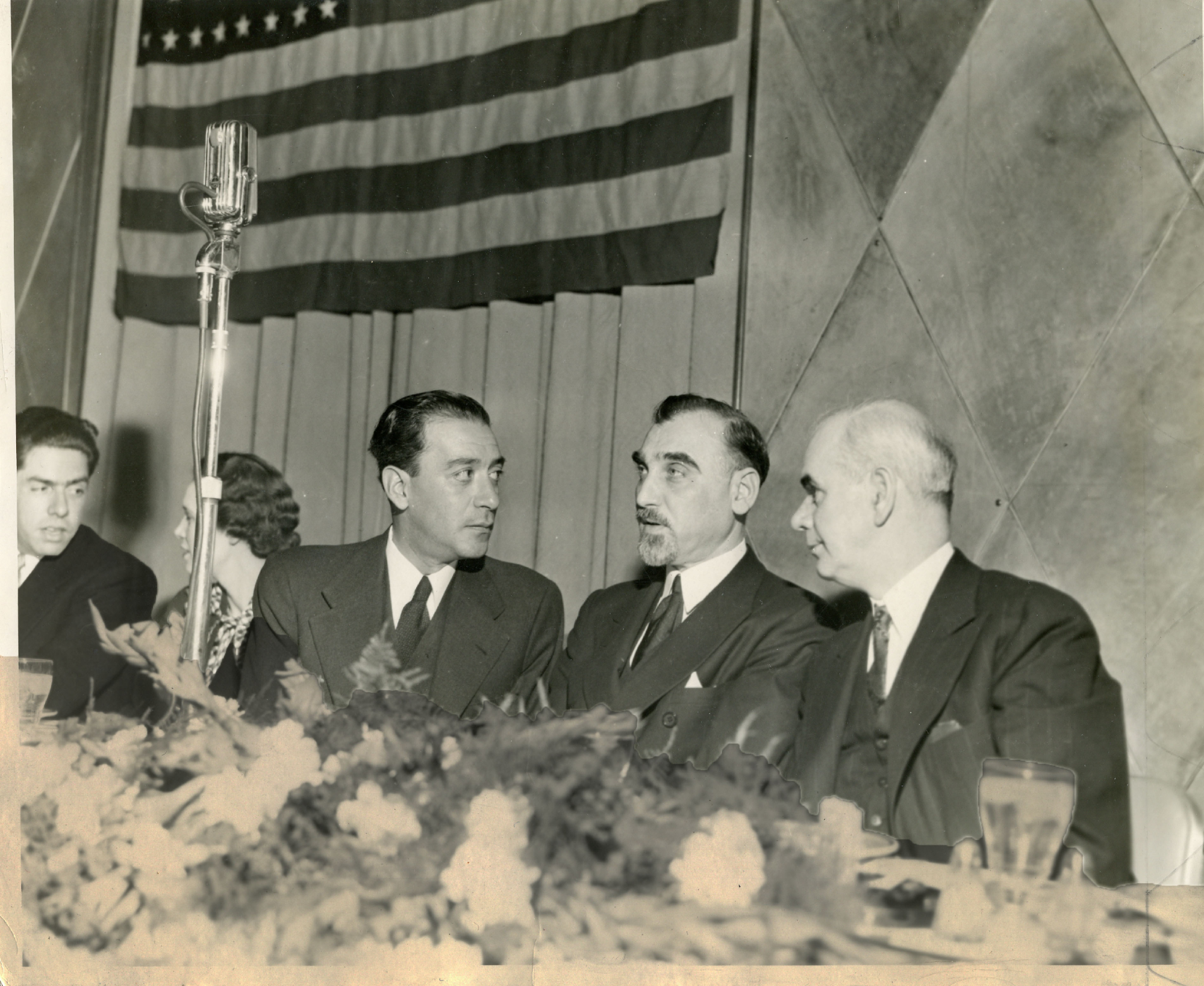 Foto en blanco y negro de un grupo de personas alrededor de una mesa

Descripción generada automáticamente